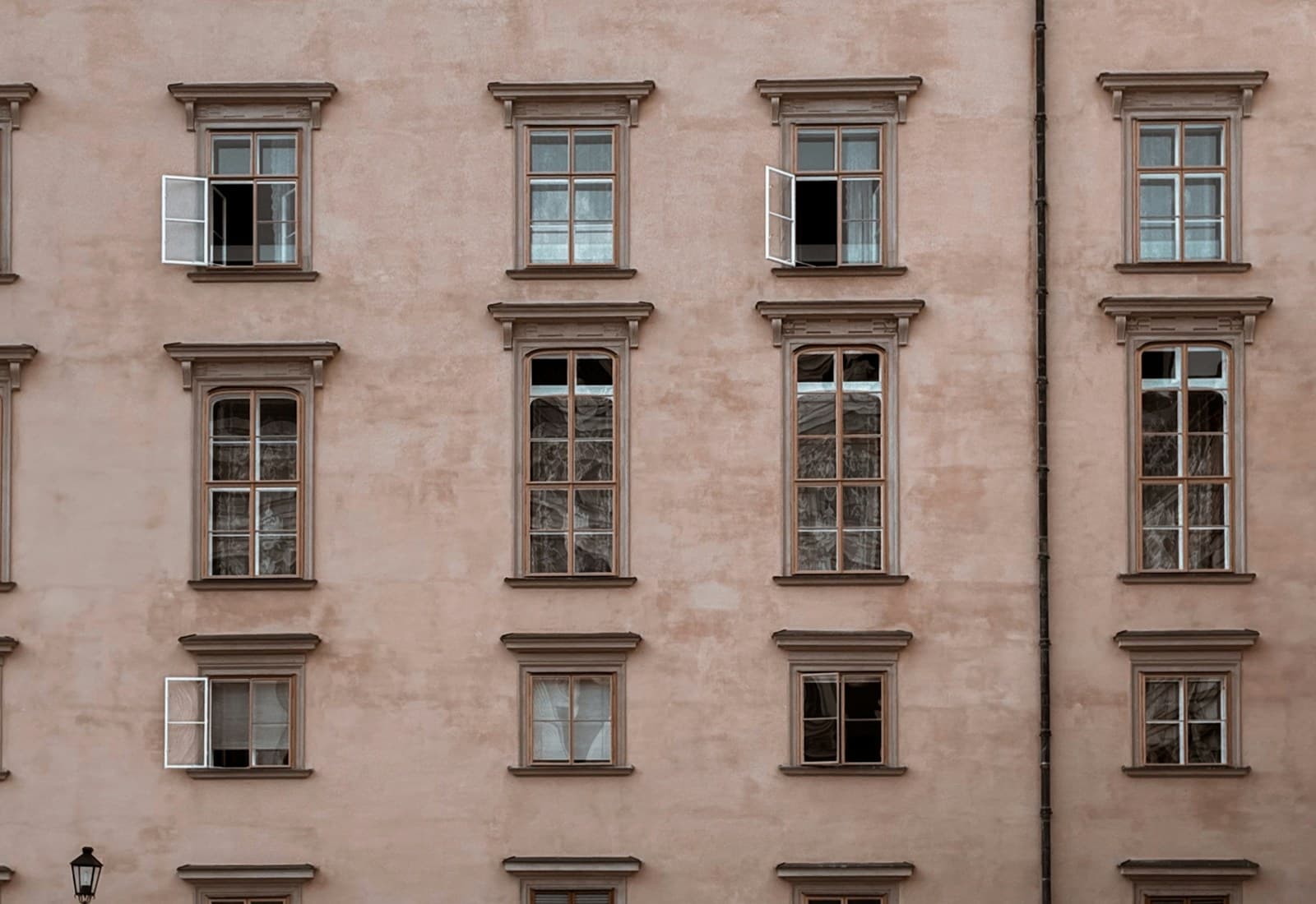 Gründerzeitfassade mit vier Fensterreihen in verwittertem rosa Putz.